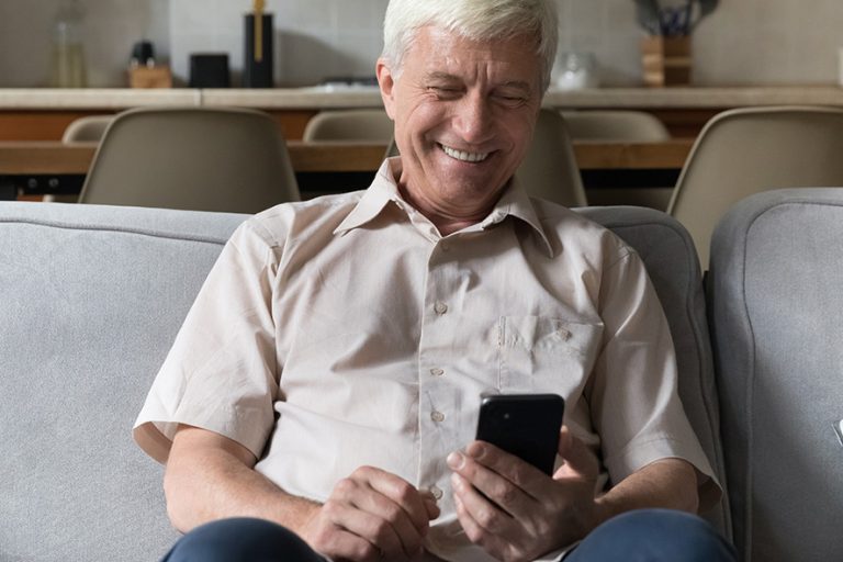 Älterer Herr lachend am Smartphone