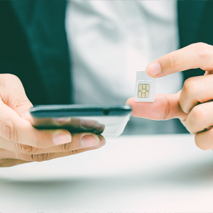Hände einer Person im Anzug, die in der rechten Hand ein Handy hält und in der linken Hand die SIM-Karte