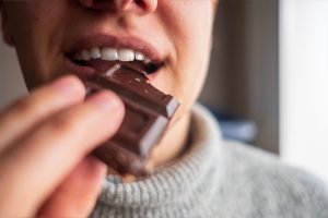 Mann beißt von Stück Schokolade ab
