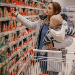 Frau mit Kleinkind auf dem Arm im Supermarkt