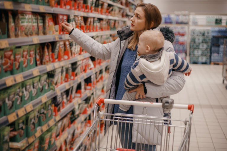 Frau mit Kleinkind auf dem Arm im Supermarkt